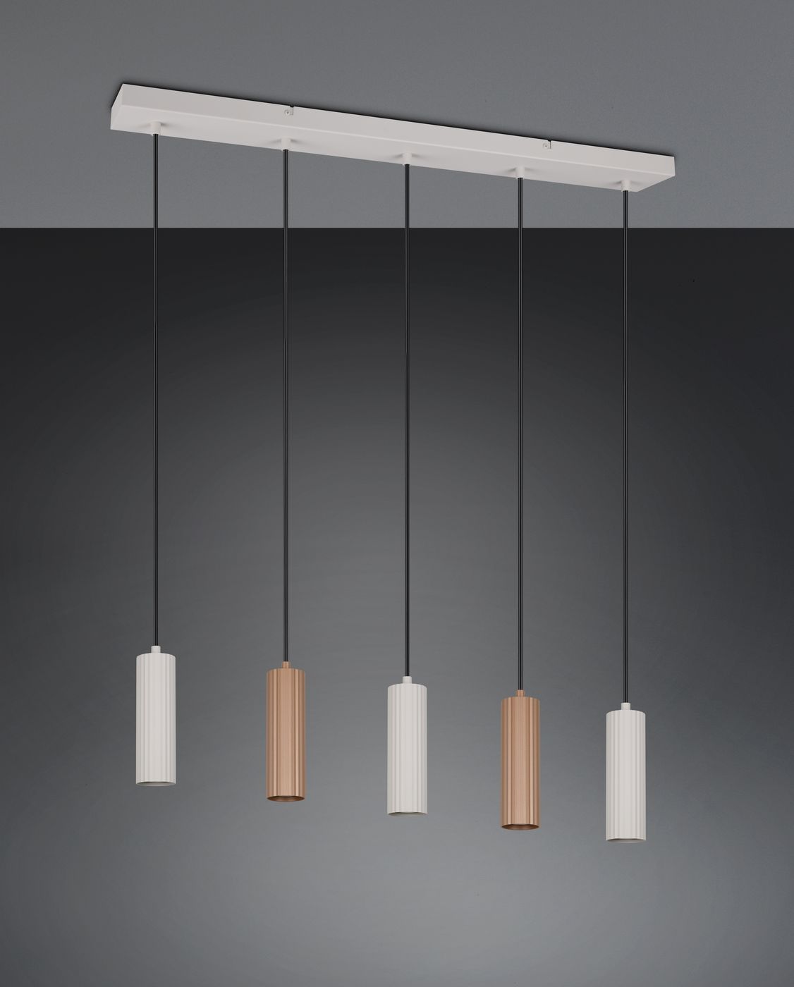 Lampa wisząca Soka z pięcioma oprawami GU10 w kolorze szarym i kawowym. Posiada cylindryczne klosze w różnych odcieniach, zawieszone na czarnych linkach, montowane do białej podstawy. Całość na ciemnym tle.