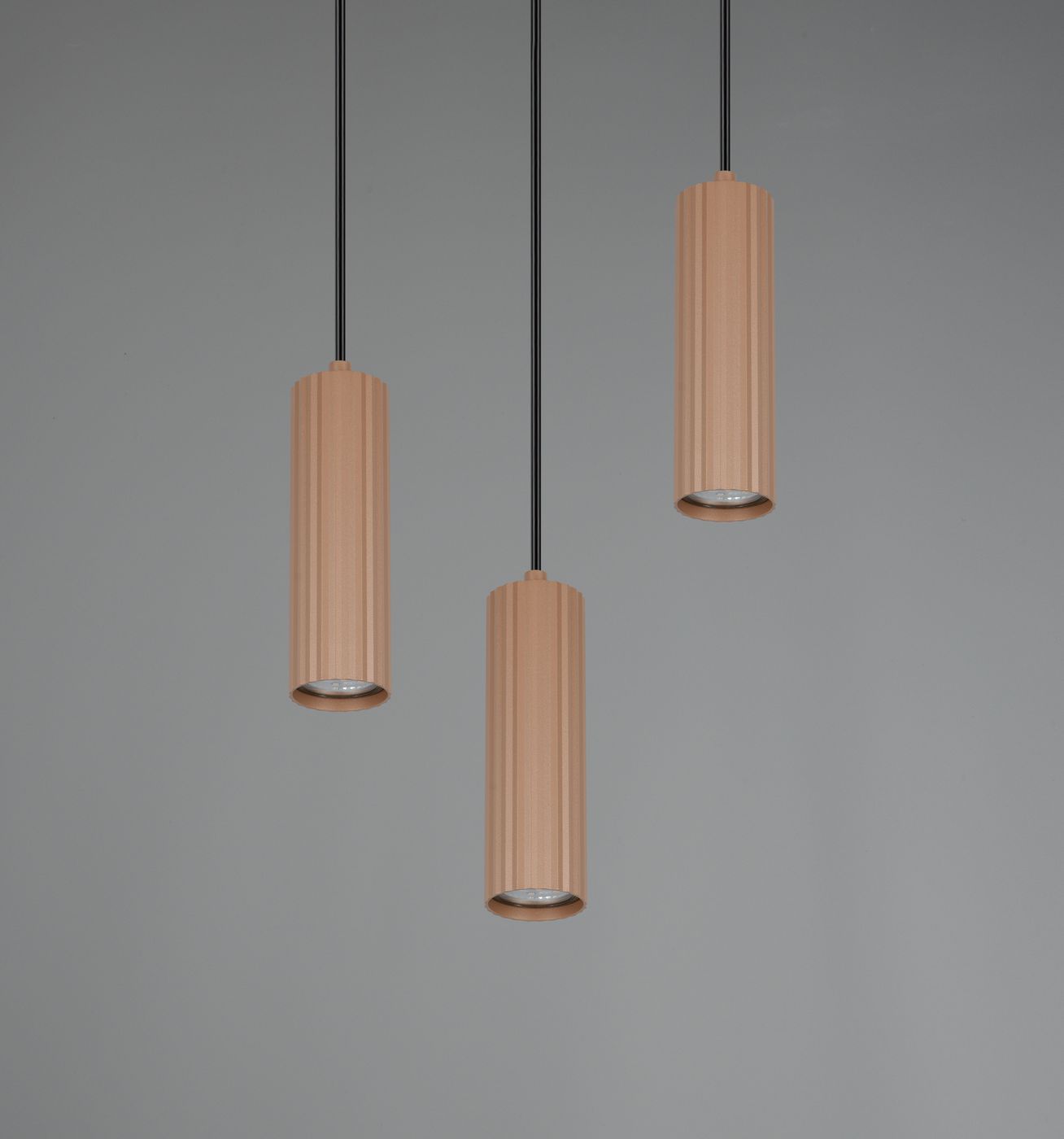Lampa wisząca Soka z trzema cylindrycznymi kloszami w odcieniu szaro-kawowym, zawieszona na czarnych przewodach. Klosze mają teksturowaną powierzchnię i otwarte końce, co umożliwia kierowanie światła w dół. Tło w jasnoszarym kolorze.