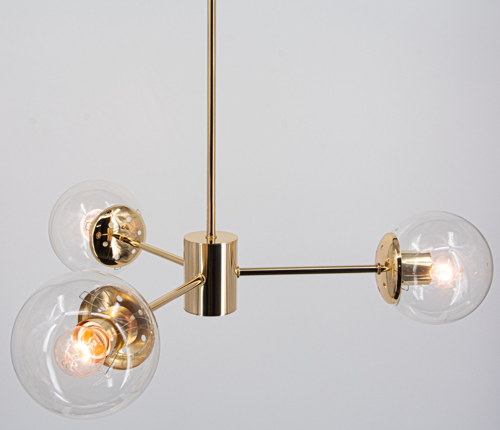 Lampa wisząca Gaja w kolorze złotym, z trzema kulistymi kloszami szklanymi. Klosze osadzone na metalowych ramionach z centralnym mocowaniem. Wymaga trzech żarówek E27. Ujęcie z góry, ukazujące szczegóły konstrukcji i źródła światła.