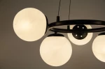 Lampa wisząca Amaro z pięcioma oprawami E14 w kolorze czarnym. Szklane klosze w kształcie kul, matowe, zamocowane na okrągłej, czarnej ramie. Ujęcie z dołu, ukazujące detale konstrukcji oraz sposób mocowania.