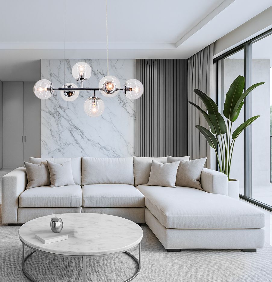 Lampa wisząca Paco z chromowanym wykończeniem, wyposażona w sześć oprawek E14, zawieszona w centralnej części pomieszczenia. W tle widoczny jasny salon z szarym narożnikiem, okrągłym stołem i dużymi oknami.