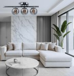 Lampa sufitowa Argo 3xE14 w chromowanej obudowie, z trzema szklanymi kloszami. Ujęcie z góry, zawieszona nad jasną sofą w nowoczesnym wnętrzu z marmurową ścianą i dużymi oknami. W tle widoczna roślina doniczkowa.