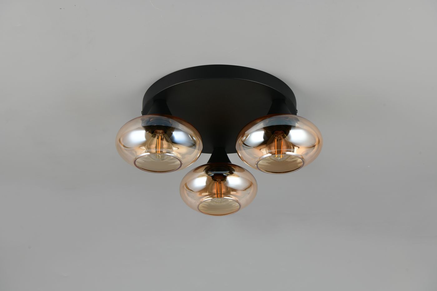 Lampa sufitowa Divina z trzema kloszami E14 w kolorze czarnym i bursztynowym. Klosze o okrągłym kształcie, transparentne z metalicznymi akcentami, zamontowane na okrągłej podstawie. Ujęcie frontalne, pokazujące detale oświetlenia.