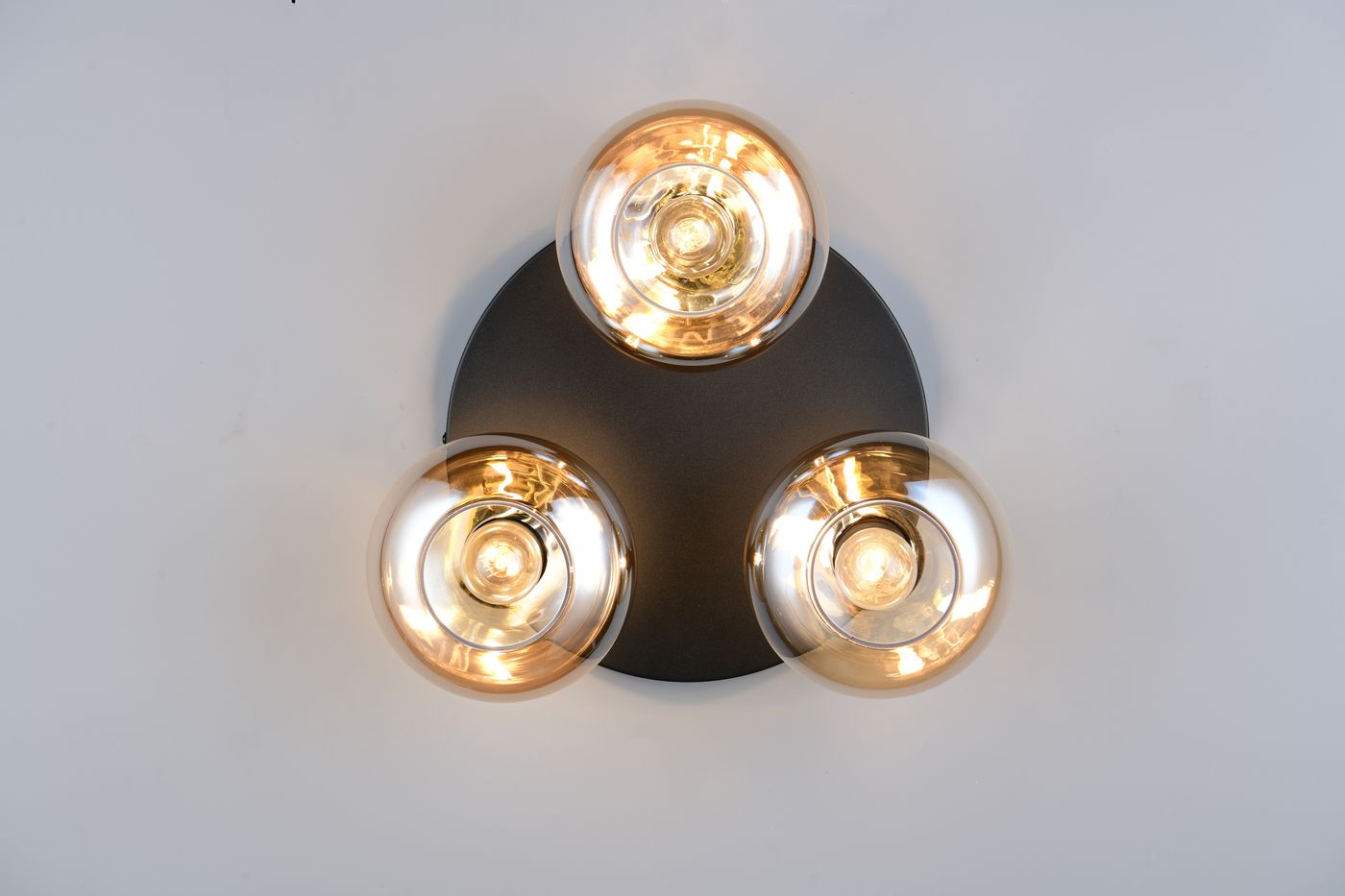 Lampa sufitowa Divina 3xE14 w kolorze czarnym, z trzema bursztynowymi kloszami. Ujęcie z góry, prezentujące okrągłą podstawę i szklane klosze, które emitują ciepłe światło. Idealna do nowoczesnych wnętrz.