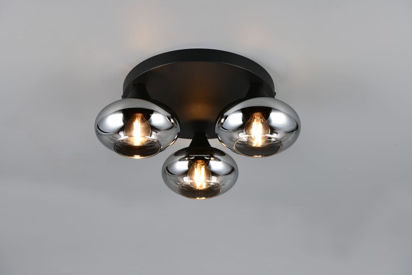 Czarna lampa sufitowa Divina z trzema oprawami E14, z przydymionymi, metalicznymi kloszami w kształcie kul. Ujęcie frontalne, produkt zamontowany na suficie, z widocznymi żarówkami. Proste tło podkreśla nowoczesny design.