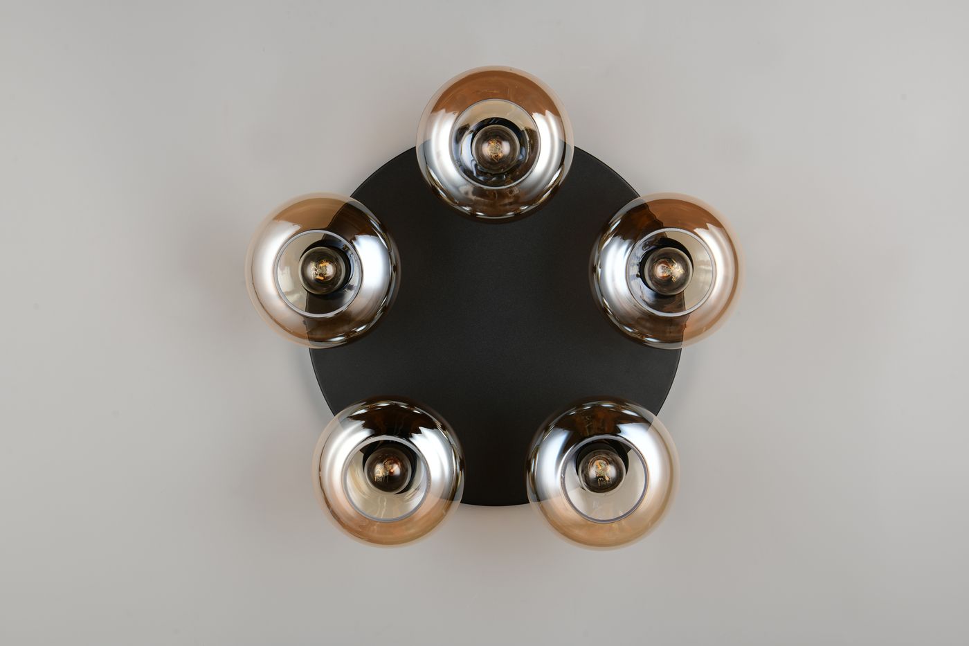 Lampa sufitowa Divina z pięcioma kloszami E14 w kolorze bursztynowym, zamontowana na okrągłej, czarnej podstawie. Klosze mają metaliczny połysk, a lampa jest widoczna z góry, ukazując jej symetryczny układ.