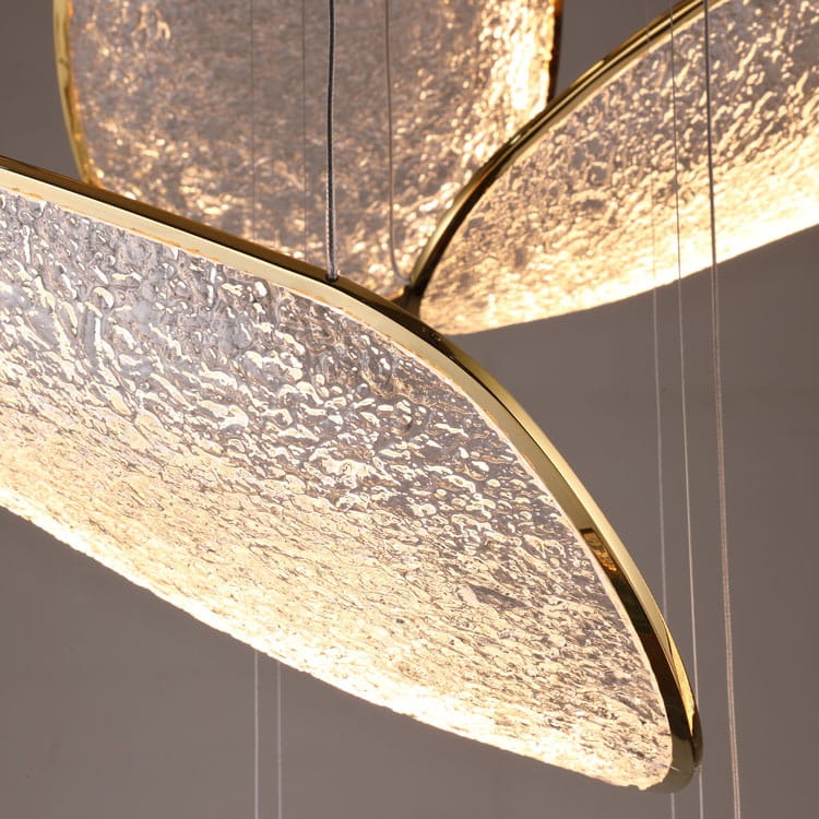 Lampa wisząca Empire z siedmioma diodami LED, oświetlenie 121W. Złota oprawa z przezroczystymi, teksturowanymi kloszami, wisząca w dynamicznej aranżacji. Klosze o opływowym kształcie, zawieszone na cienkich linkach, emitujące ciepłe światło.