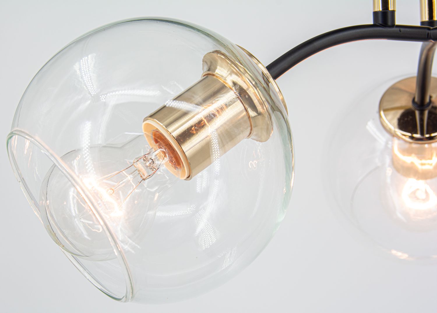 Lampa sufitowa Elba 3xE27 w kolorze czarnym i złotym. Szklane klosze w kształcie kul, metalowe mocowania w odcieniu złotym. Widok z góry, ukazujący szczegóły mocowania żarówki. Na białym tle.