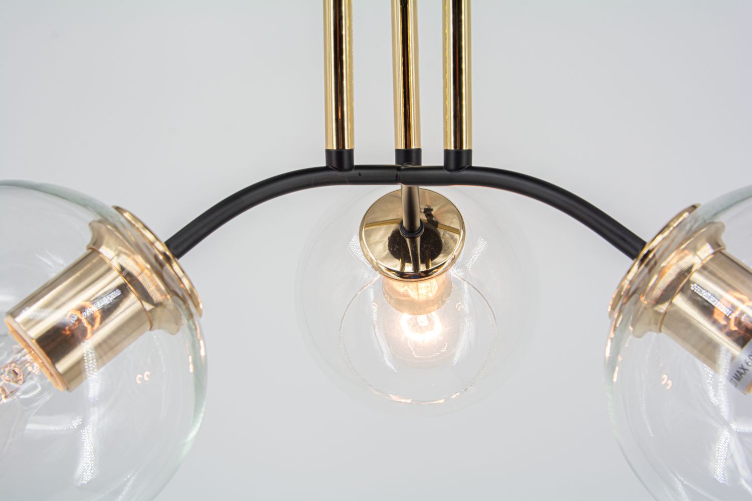 Lampa sufitowa Elba 3xE27 w kolorze czarnym i złotym, z trzema okrągłymi kloszami ze szkła, umieszczona na metalowej konstrukcji. Ujęcie z góry, z widocznym źródłem światła, podkreślającym elegancki design.