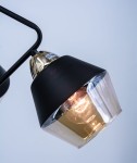 Czarny żyrandol Clovis z trzema oprawami E27, z metalowym kloszem w złotym kolorze, w zbliżeniu na jeden z kloszy. Widoczny błyszczący detal i przezroczysta dolna część klosza. Ujęcie z boku, na jasnym tle.