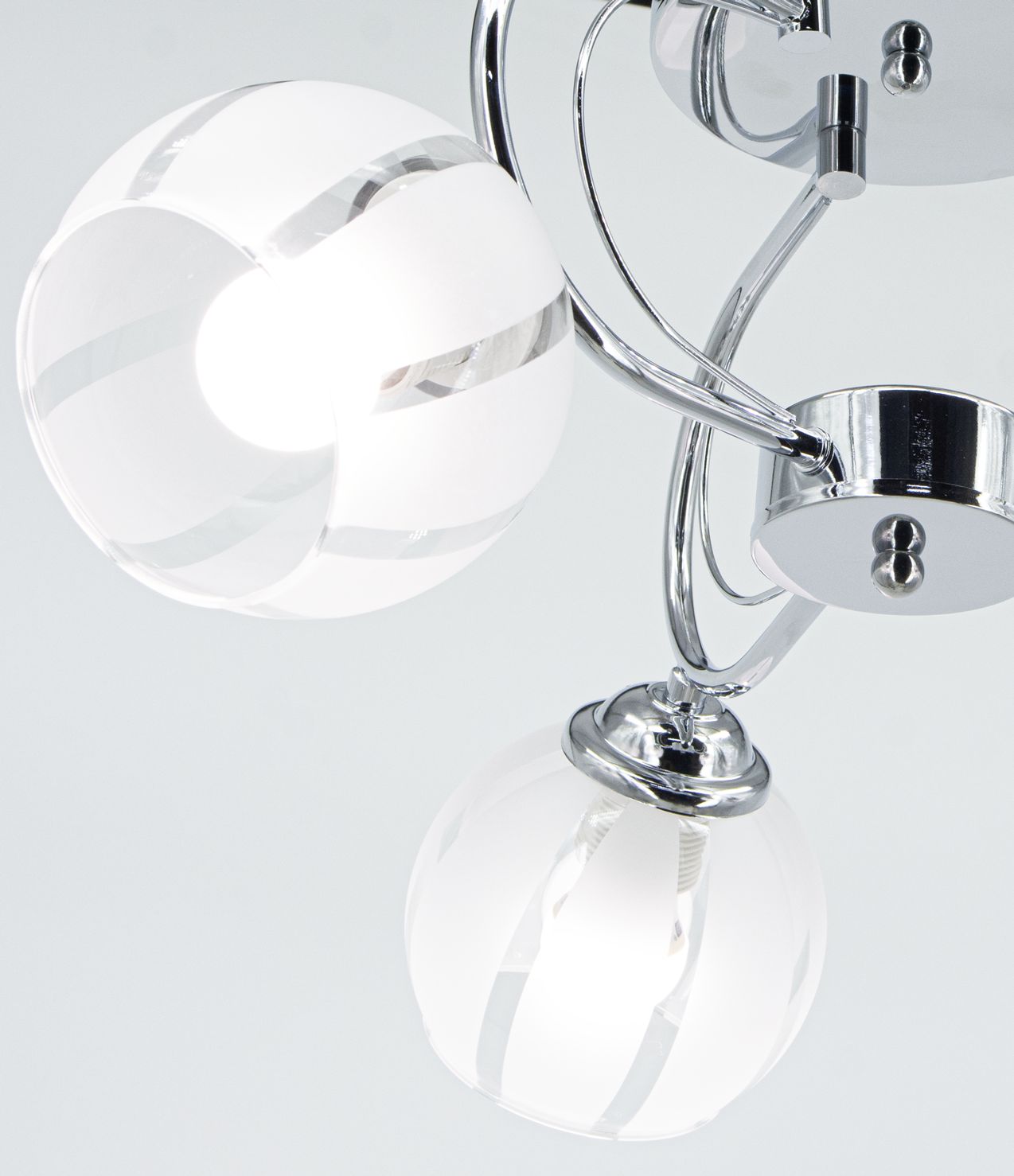 Lampa sufitowa Ruby z trzema kloszami E27, chromowana, z kulistymi, białymi kloszami z przezroczystymi pasami. Ujęcie z bliska, pokazujące detale mocowania oraz linii konstrukcyjnej. Tło jasne, minimalistyczne.