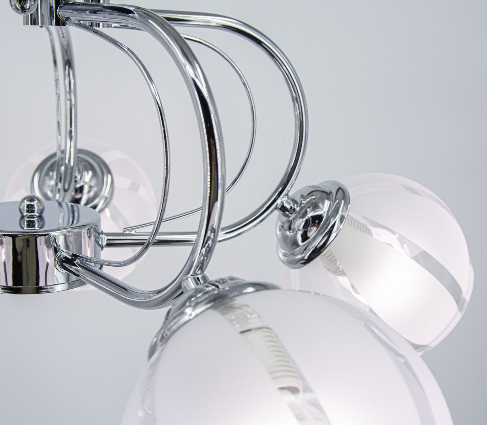 Lampa sufitowa Ruby z pięcioma kloszami E27 w chromowanej oprawie. Klosze mają półprzezroczystą teksturę, a całość ma nowoczesny, elegancki design. Ujęcie z góry ukazuje detale mocowania i kształt kloszy.
