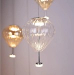 Lampa wisząca Palloncini 2xLED 6W o przezroczystym kloszu w kształcie balonu, z metalowym uchwytem. Zawieszona na cienkim przewodzie, emituje ciepłe światło, idealna do nowoczesnych wnętrz. Tło w jasnym kolorze.