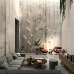 Kinkiet Merano 2xLED 10W w kolorze złotym, montowany na ścianie. Widoczny w nowoczesnym wnętrzu z szaro-betonowymi ścianami, oświetlający przestrzeń. W tle zielona roślina oraz meble w odcieniach szarości i brązu.