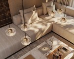 Lampa wisząca Lipari 3xLED 22W w białym kolorze z przezroczystymi kloszami i złotymi detalami, zawieszona na czarnych linkach. Widok z góry na elegancki salon z jasną sofą i marmurowym stolikiem.