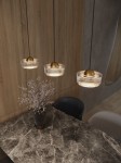 Lampa wisząca Lipari z trzema źródłami LED 22W w kolorze białym. Szklane klosze w formie okrągłych misek z metalowymi, złotymi elementami, zawieszone na cienkich linkach. W tle widoczny stół z marmurowym blatem i wazon z kwiatami.