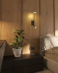 Ibiza kinkiet 2xLED 9W w kolorze czarnym, zamontowany na drewnianej ścianie. Posiada dwa źródła światła, jedno w górnej części, drugie na ruchomej końcówce. W tle widoczna szafka nocna z rośliną w doniczce oraz część łóżka.