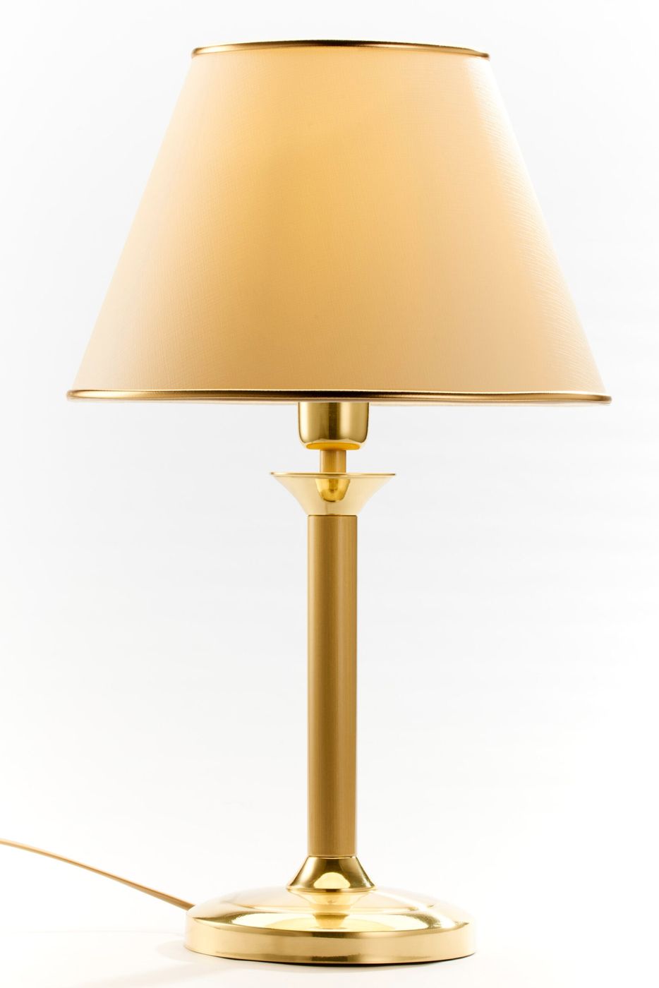 Lampa stołowa w kolorze mosiądzu satynowanego z kloszem w odcieniu jasnego beżu. Stoi na okrągłej podstawie, z prostym, cylindrycznym trzonem. Klosz ma stożkowy kształt, wykończony złotą obręczą u góry. Kabel widoczny z boku.