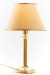 Lampa stołowa w kolorze mosiądzu satynowanego z kloszem w odcieniu jasnego beżu. Stoi na okrągłej podstawie, z prostym, cylindrycznym trzonem. Klosz ma stożkowy kształt, wykończony złotą obręczą u góry. Kabel widoczny z boku.