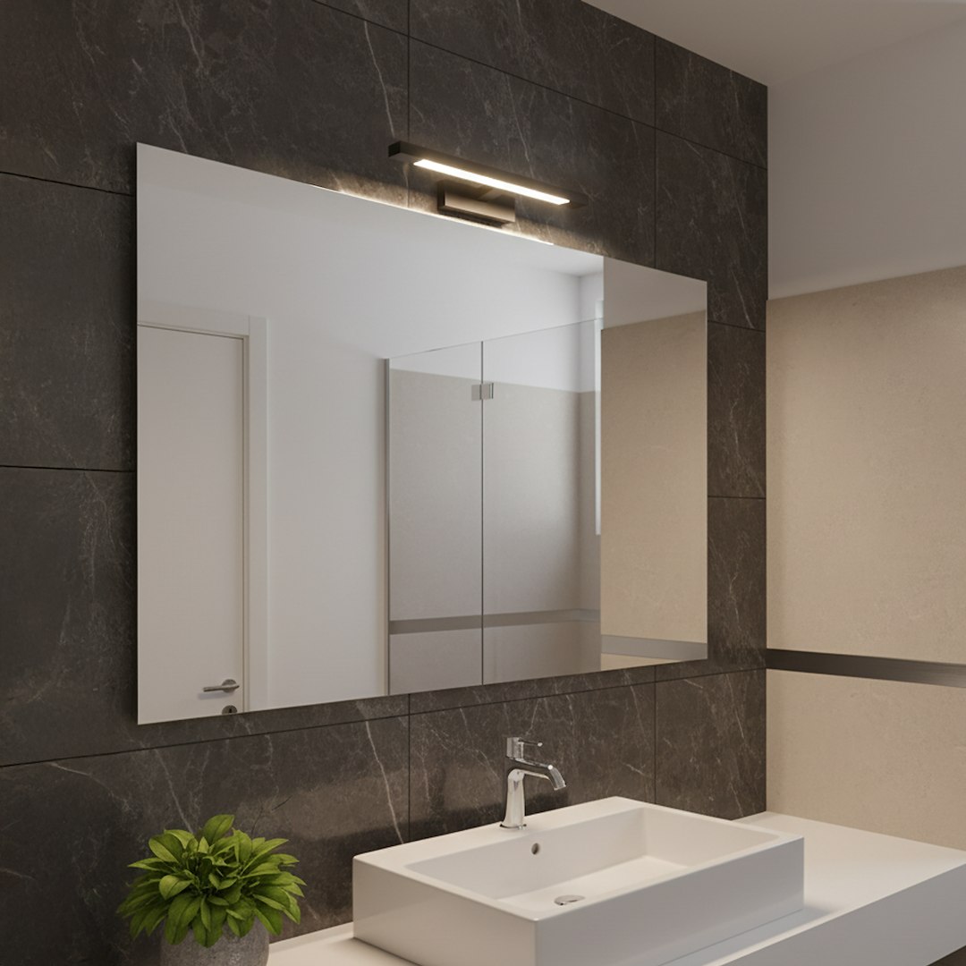 Kinkiet Klimt L40 LED 8W CCT IP44 w kolorze czarnym, montowany nad lustrem w nowoczesnej łazience. Oświetlenie LED o prostym, minimalistycznym designie, umieszczone na tle ciemnej, marmurowej ściany.