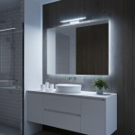 Kinkiet Klimt L40 LED 8W CCT IP44 w kolorze białym, zamontowany nad lustrem w nowoczesnej łazience. Oświetlenie o prostokątnym kształcie, emitujące jasne światło, w otoczeniu białej umywalki i rośliny w doniczce.