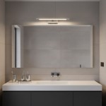 Kinkiet Klimt L40 LED 8W CCT IP44 w chromowanej obudowie, zamontowany nad lustrem w nowoczesnej łazience. Oświetlenie ma prostą, liniową formę, z ciepłym światłem, umieszczone na gładkiej, jasnej ścianie.