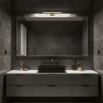 Kinkiet Klimt L40 LED 8W CCT IP44 w kolorze złotym, zamontowany nad lustrem w nowoczesnej łazience. Prosta, prostokątna forma z delikatnym podświetleniem, na tle ciemnych płytek i minimalistycznych mebli.