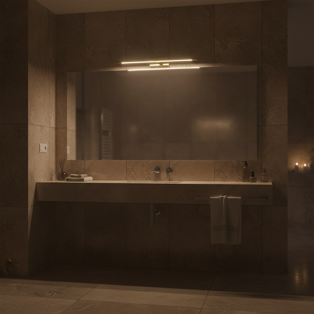 Kinkiet Klimt L60 LED 12W CCT IP44 w złotym kolorze, zamontowany nad lustrem w łazience. Wyposażony w subtelne oświetlenie, idealny do przestrzeni o podwyższonej wilgotności. Ujęcie frontalne, w tle widoczne elementy łazienkowe.