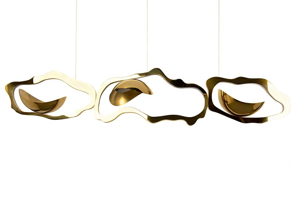 Lampa wisząca LED Chain 210 w kolorze złotym, o unikalnym, falistym kształcie. Składa się z trzech elementów, z widocznymi połyskującymi detalami. Zawieszona na cienkich linkach, prezentuje nowoczesny design idealny do wnętrz.
