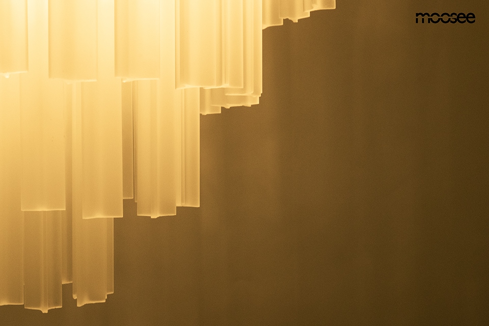Lampa wisząca Gordon 80, złota, z 21 źródłami E14. Przeźroczyste, prostokątne elementy zwisają w dół, tworząc efektowną kompozycję. Ujęcie z dołu, na jednolitym tle, eksponujące detale struktury i materiału.