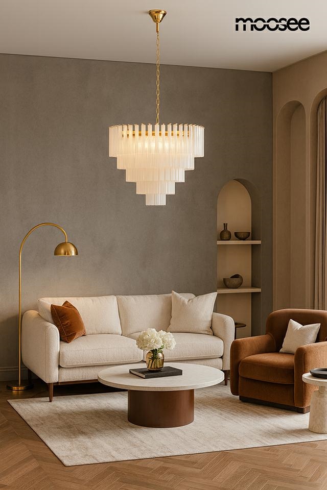 Lampa wisząca Gordon 80 w złotym kolorze, z 21 miejscami na żarówki E14, o geometrycznym kształcie z przezroczystymi, szklanymi kloszami. Zawieszona w eleganckim wnętrzu z sofą i stolikiem kawowym.