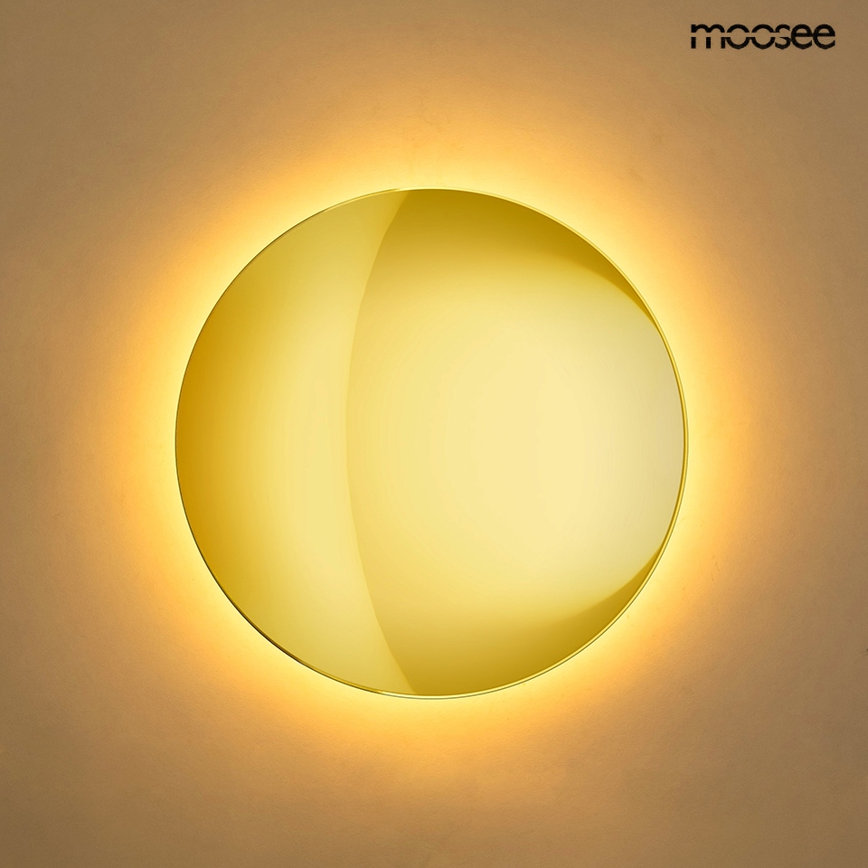 Kinkiet LED Shadow Sun 25 w kolorze złotym, o okrągłym kształcie, oświetlający ścianę ciepłym światłem (3000K). Montowany na ścianie, z połyskującą powierzchnią, emitującą delikatne halo światła wokół. Logo producenta w prawym górnym rogu.
