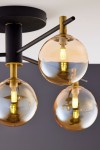 Lampa sufitowa Figaro 4xG9 w kolorze czarnym z bursztynowymi kloszami. Konstrukcja z metalowych prętów, z widocznymi żarówkami LED. Ujęcie z góry, pokazujące detale kloszy i mocowania. Tło w odcieniu szarości.