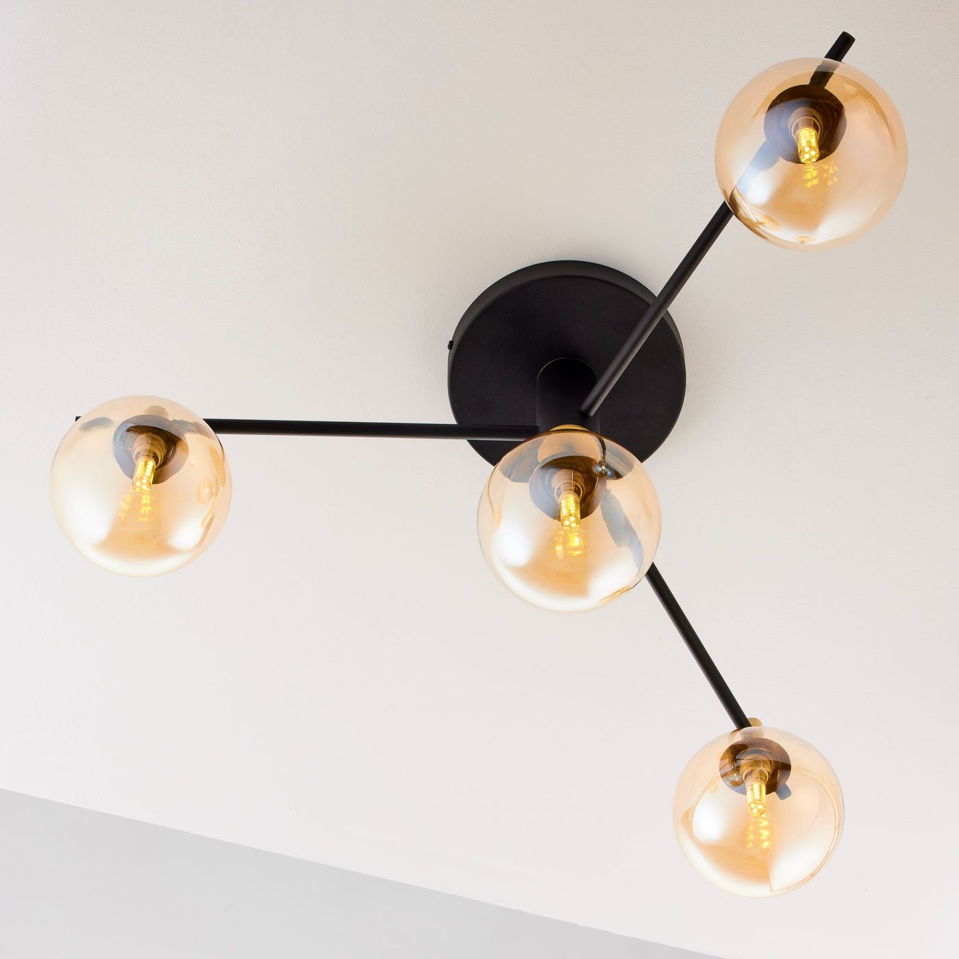 Lampa sufitowa Figaro 4xG9 w kolorze czarnym, z czterema bursztynowymi kloszami. Ułożona w formie rozłożonej, z metalowym mocowaniem i widocznymi żarówkami. Klosze mają okrągły kształt, a całość jest zamontowana na suficie.