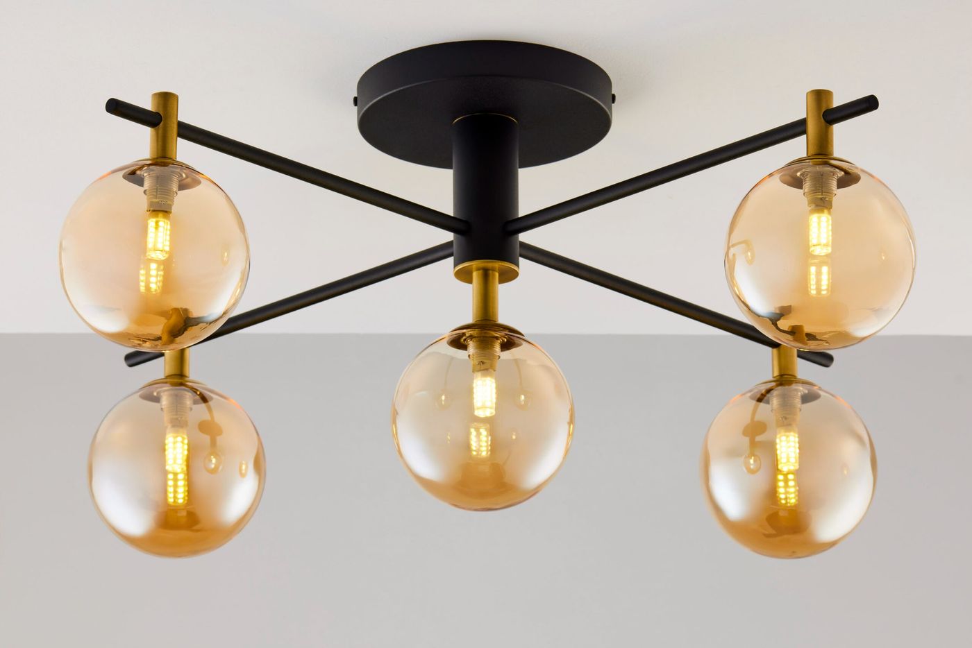 Lampa sufitowa Figaro 5xG9 w kolorze czarnym z bursztynowymi kloszami. Oferuje nowoczesny design z metalowym stelażem i pięcioma okrągłymi, transparentnymi kloszami, umieszczona na okrągłej podstawie, widoczna z boku.