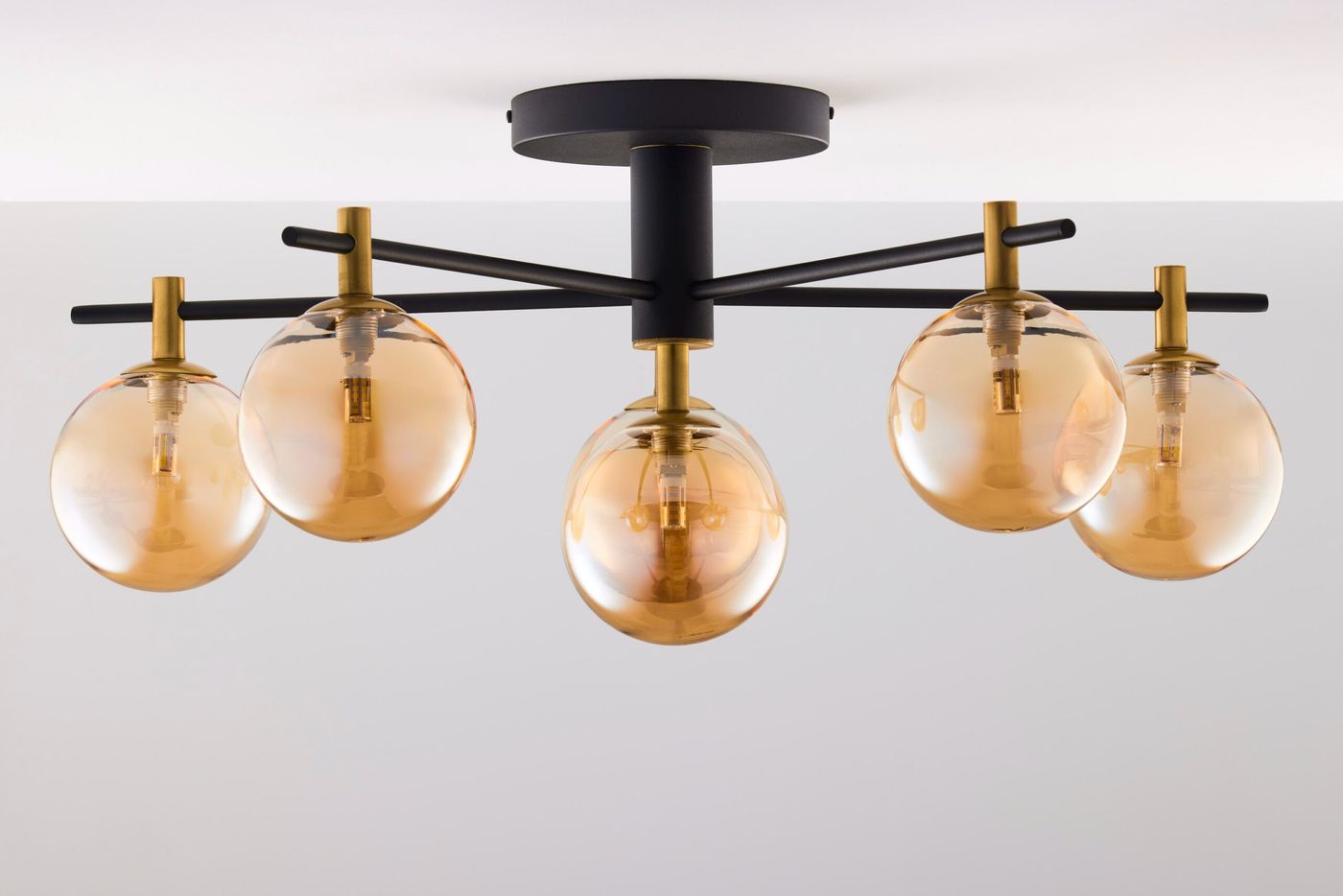 Lampa sufitowa Figaro w kolorze czarnym z sześcioma bursztynowymi kloszami. Klosze mają okrągły kształt i są zawieszone na czarnych, metalowych ramionach. Montaż sufitowy, elegancki design, nowoczesny styl.