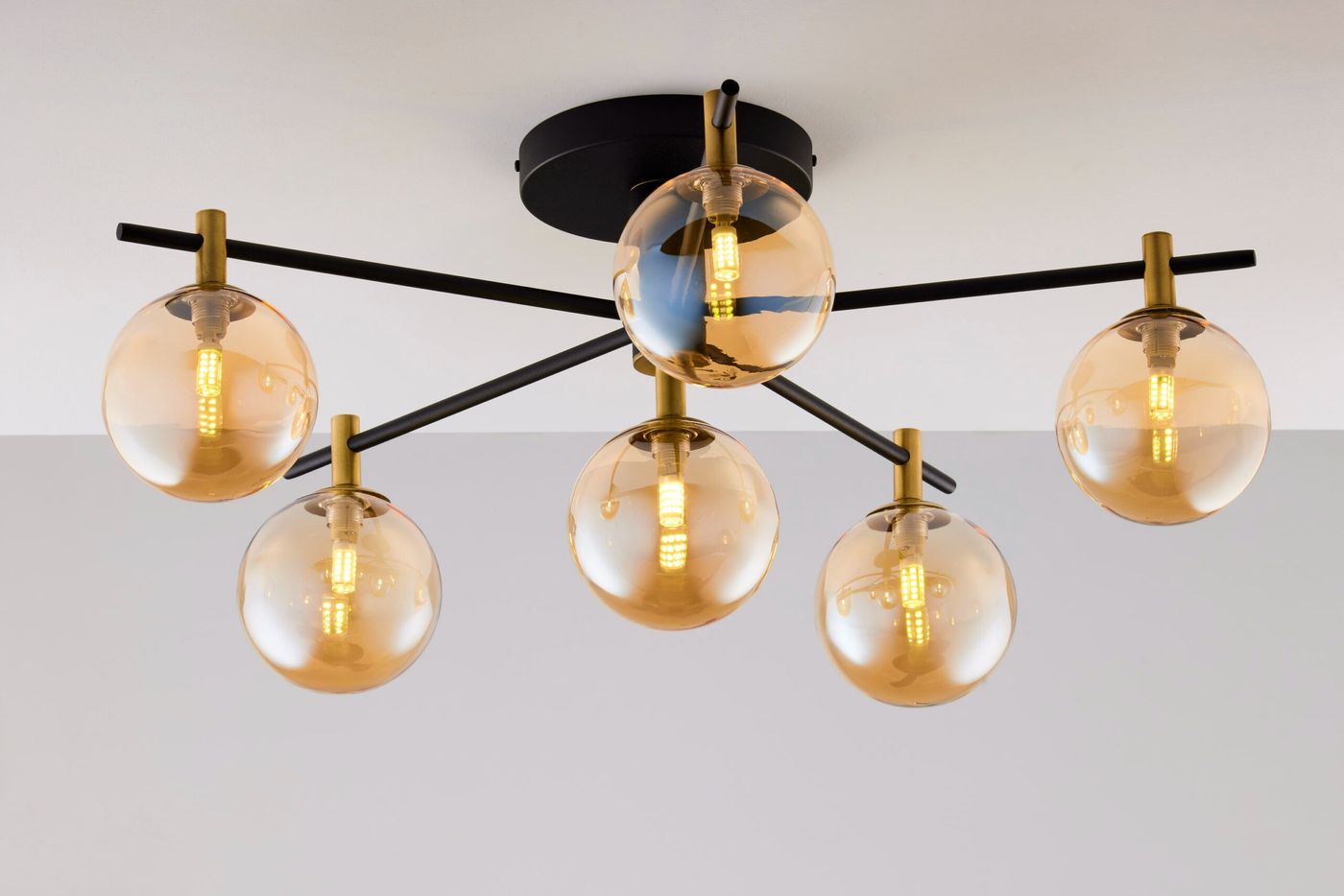 Lampa sufitowa Figaro w kolorze czarnym z bursztynowymi kloszami, z sześcioma źródłami światła G9. Ułożona na stropie, z metalowymi ramionami w kolorze złotym, nadająca nowoczesny charakter wnętrzu.