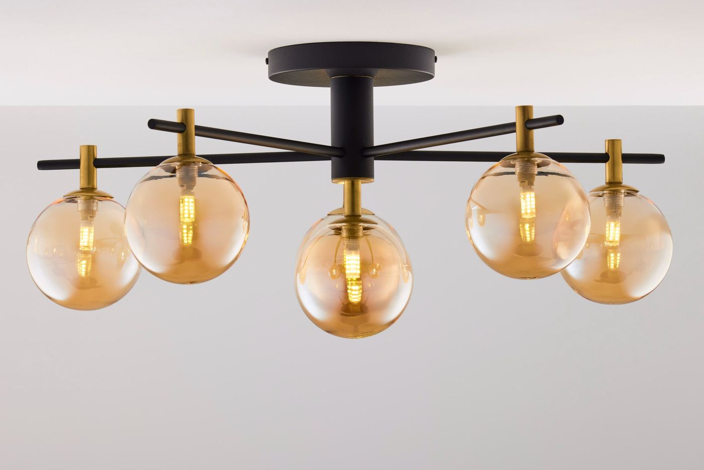 Lampa sufitowa Figaro z sześcioma oprawami G9, w czarnej metalowej konstrukcji z złotymi detalami. Szklane klosze w bursztynowym kolorze, zamontowane na rozłożystych ramionach, widoczna z góry. Idealna do nowoczesnych wnętrz.