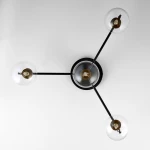 Lampa sufitowa Figaro 4xG9 w kolorze czarnym z transparentnymi kloszami. Ułożona w kształcie gwiazdy, z czterema żarówkami umieszczonymi na długich, czarnych ramionach, mocowana do stropu. Metalowa podstawa z elementami mosiężnymi.