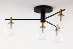 Lampa sufitowa Figaro z czarnym metalowym stelażem i transparentnymi szklanymi kloszami. Posiada cztery źródła światła G9, rozmieszczone na poziomej metalowej rurze, z elementami w kolorze złotym. Ujęcie z dołu na zamontowaną lampę.