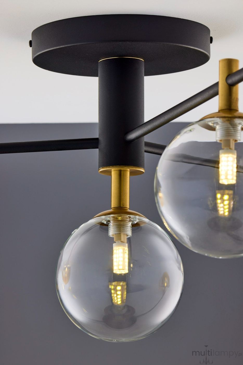 Lampa sufitowa Figaro w kolorze czarnym z transparentnymi kloszami. Posiada cztery gniazda G9, metalową konstrukcję z złotymi detalami. Widok z góry, ukazujący połączenie kloszy ze źródłami światła oraz montaż na suficie.