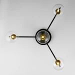 Lampa sufitowa Figaro z czarnym metalowym stelażem i czterema przezroczystymi kloszami. Ujęcie z góry, z widocznymi żarówkami G9 i złotymi detalami. Produkt w stylu nowoczesnym, montowany na suficie.