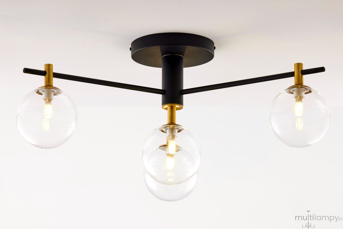 Lampa sufitowa Figaro w kolorze czarnym z przezroczystymi kloszami. Posiada cztery oprawy G9, metalową konstrukcję z elementami w złotym kolorze. Ujęcie z dołu, ukazujące położenie kloszy oraz detal konstrukcji.