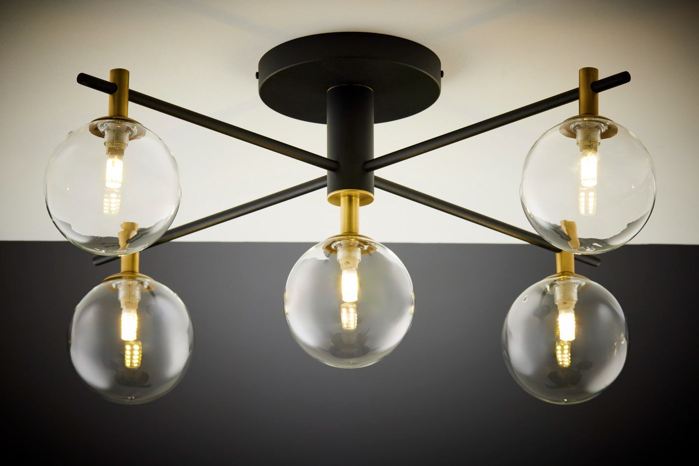 Czarna lampa sufitowa Figaro z pięcioma kulistymi kloszami z przezroczystego szkła, osadzona na metalowej konstrukcji z elementami złotymi. Produkt zamontowany na sufit, widok z dołu. Wymiary i szczegóły montażu nie są podane.