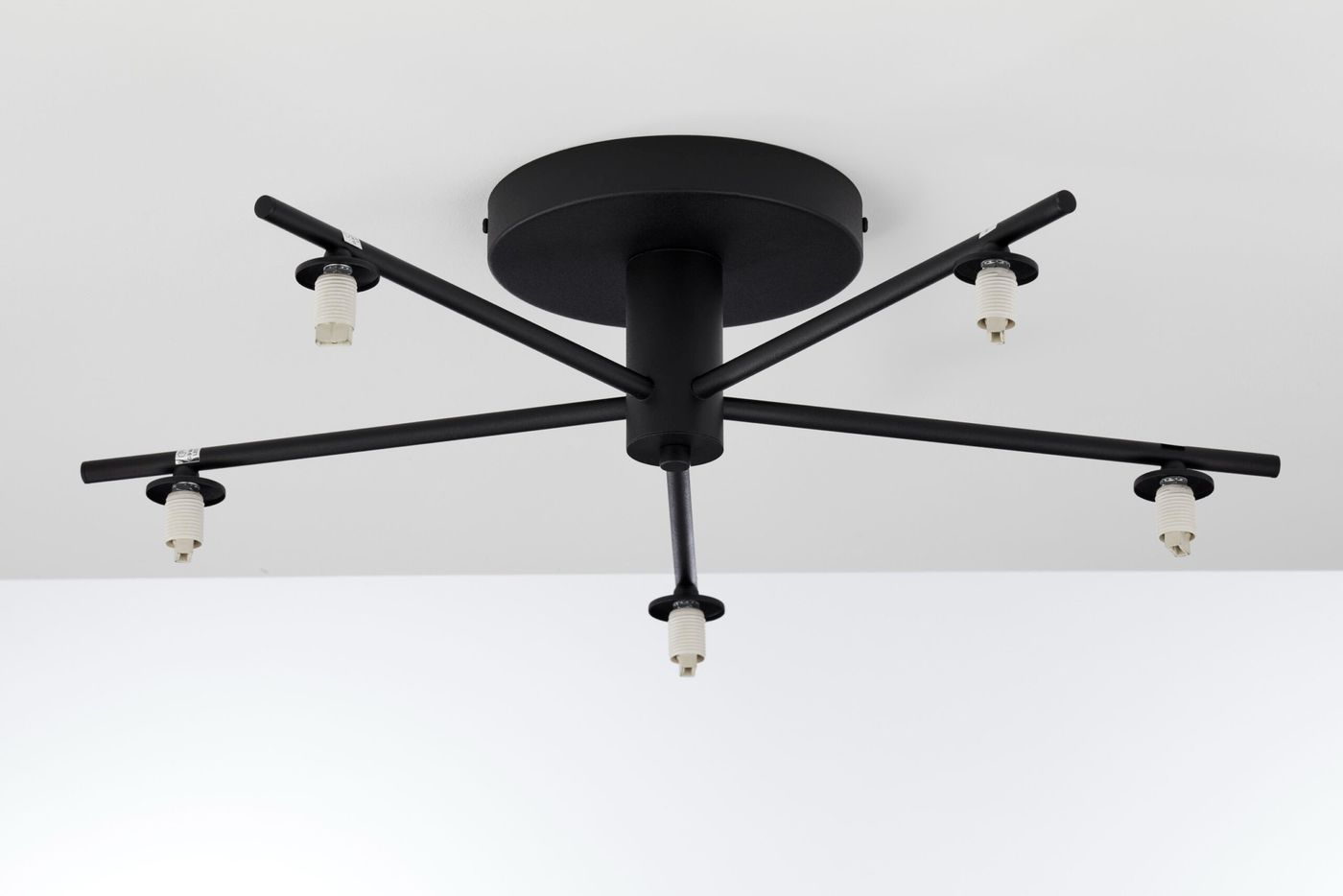 Lampa sufitowa Prato w kolorze czarnym z pięcioma gniazdami G9, zamontowana na okrągłej podstawie. Uchwyty w formie prostokątnych ramion rozciągają się w różnych kierunkach, tworząc nowoczesny design. Ujęcie z góry.