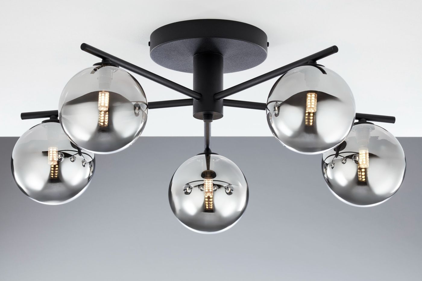 Lampa sufitowa Prato z pięcioma kulistymi kloszami w dymnym kolorze, zamontowana na czarnej podstawie. Klosze z przezroczystego szkła odsłaniają źródła światła, układ w formie rozłożonych ramion.