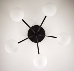 Lampa sufitowa Prato, czarna z pięcioma białymi kloszami w kształcie kul. Ujęcie z góry, ukazujące czarną podstawę oraz rozłożone ramiona. Idealna do nowoczesnych wnętrz.