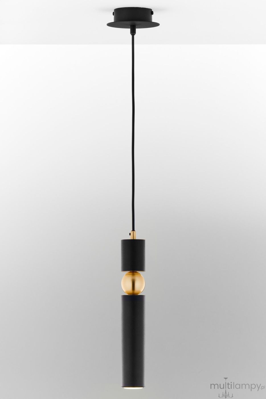 Lampa wisząca Alas, czarna, z metalowym wykończeniem w kolorze złotym. Ma cylindryczny kształt, z długim przewodem, zawieszona na okrągłej podstawie. Źródło światła GU10 umieszczone w dolnej części. Tło proste, jasne.