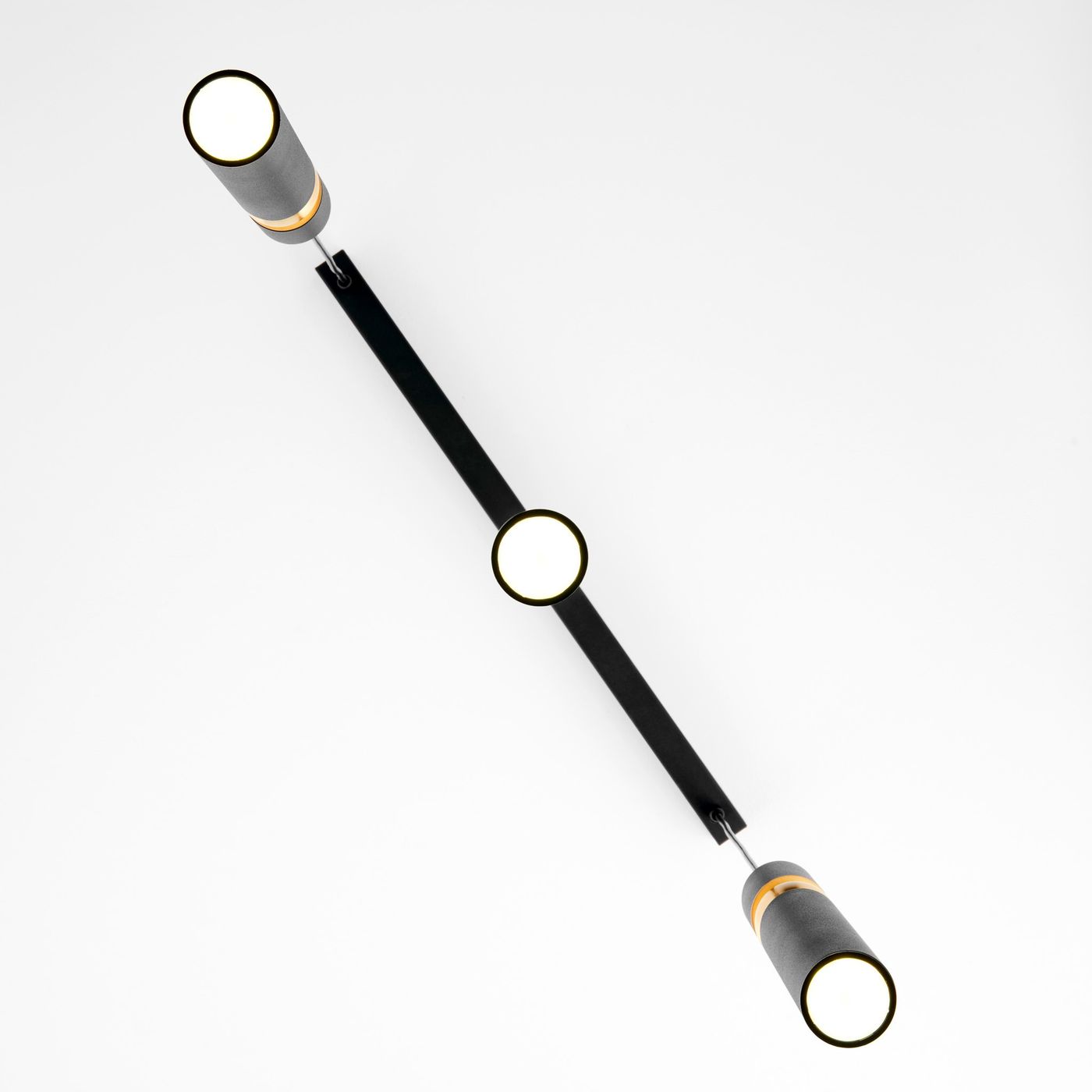 Lampa wisząca Alas 3xGU10 w kolorze czarnym z metalowym stelażem. Posiada trzy cylindryczne klosze z białym źródłem światła, rozmieszczone na prostokątnym ramieniu. Ujęcie z góry, na jednolitym tle.