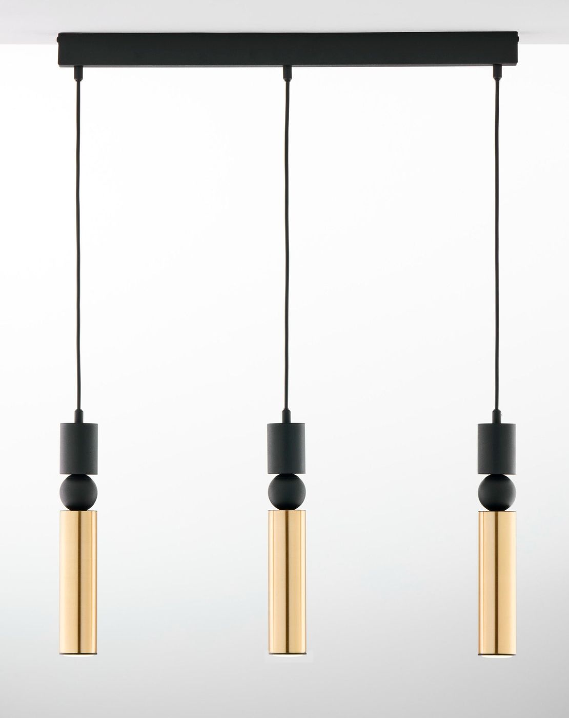 Lampa wisząca Alas 3xGU10 w kolorze czarnym i złotym. Składa się z trzech cylindrycznych źródeł światła z metalicznymi, błyszczącymi elementami oraz czarnymi detalami. Ułożona na prostokątnej podstawie, zawieszona na cienkich kablach.